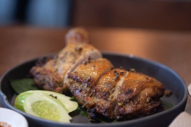 Tayland usulü ızgara tavuk, dilimlenmiş salatalık ile ahşap masada servis edilir. Odaklanmayı seç