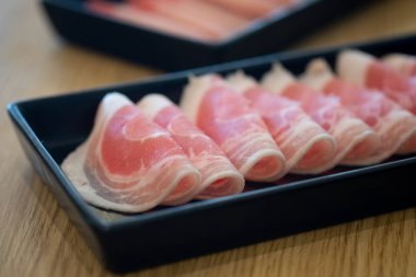 Siyah tepside taze domuz eti Shabu, sukiyaki ya da Japon yahnisi için pişmeye hazır. Seçici odak.