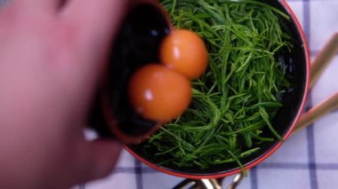 Tayland mutfağı Cha-om omleti ya da kızarmış cha-om yaprakları pişirmek için Senegalia Pennata sebzelerinin üzerine çiğ yumurta koy. Popüler bir Tayland yemeği. Yavaş çekim.