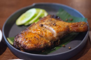 Tayland usulü ızgara tavuk, dilimlenmiş salatalık ile ahşap masada servis edilir. Odaklanmayı seç