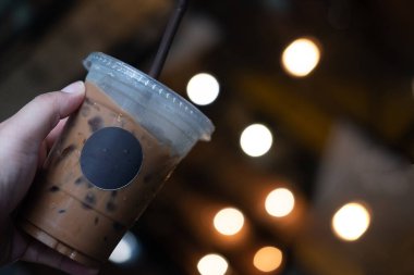 Hafif bulanık arkaplanda el ele tutuşan buzlu kahve. Tazeleyici içecek.