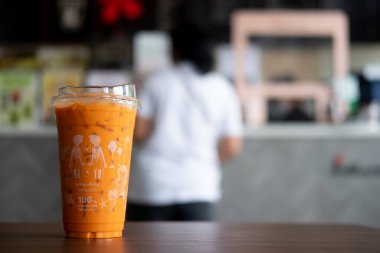 Bangkok, Tayland - 14 Ekim 2020: Kahve dükkanında ahşap masaya konmuş buzlu Tayland çayı. Inthanin kahve dükkanlarında doğal olarak çürüyebilen bir içecek kutusu..