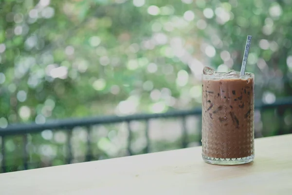 Iced Mocha coffee in glass on wood table with nature background