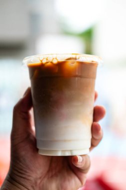 Bir bardak soğuk latte ile doldurulur. Elinde taze süt ile.