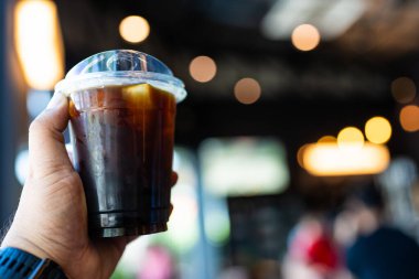 Kahve dükkanında elinde buzlu kahve tutan bir adam.