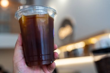 Bir kafenin yanında bir bardak soğuk sade kahve içen bir ele yaklaş.