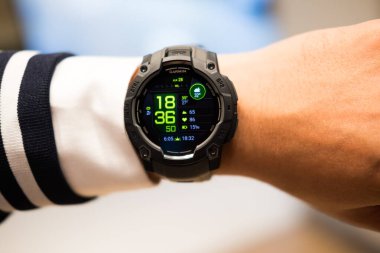 Bangkok, Tayland - 5 Eylül 2025 Garmin Instinct 3, 50mm siyah ve kömür bandı genç adamda. AMOLED ekran ile GPS akıllı izleme.
