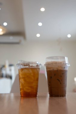 Kafedeki ahşap masada buzlu limonlu çay ve buzlu kahve.
