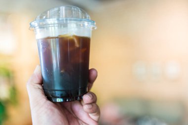 Birinin elinde bir bardak buzlu Americano tutarken yaklaş.