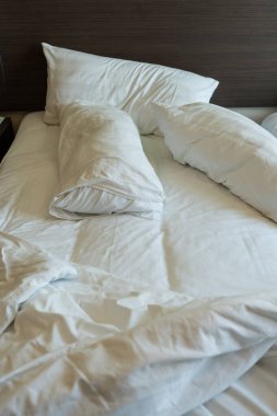 Rahat buruşmuş, buruşuk, dağınık yatak beyaz pamuk çarşaflar, yorgan, battaniye ve yastıklar.