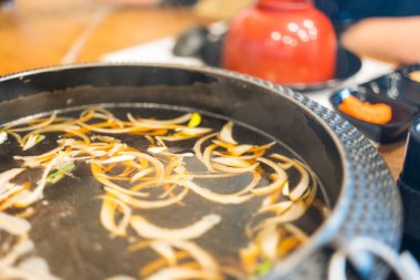 Kaynamış siyah sukiyaki çorbası ve malzemeler. Kapat.