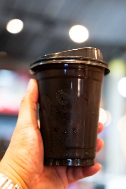 Elinde buzlu sade kahve ya da plastik bardakta americano kahvesi..