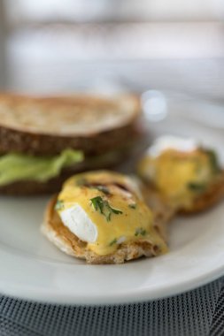 Güzel bir kaplanmış yumurta Benedict mükemmel haşlanmış yumurta üst pastırma ve bol Hollandaise soslu kızarmış İngiliz keki.