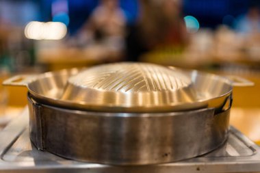 Izgara domuz eti ve et için kömür sobası üzerine boş metalik pirinçli barbekü tavası.