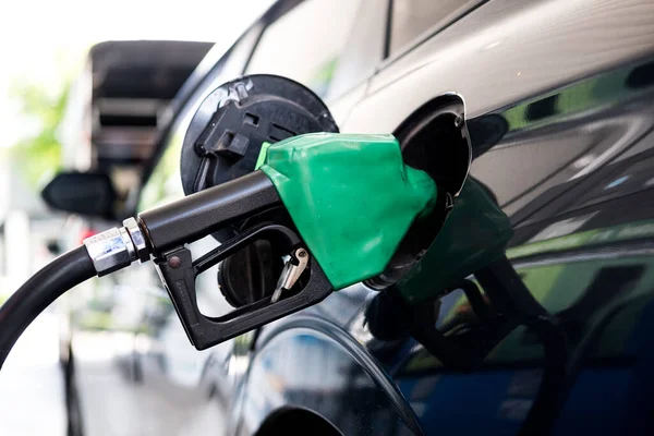 Benzin istasyonunda, benzin deposuna yerleştirilmiş yeşil yakıt pompalı gri bir arabayı kapat.