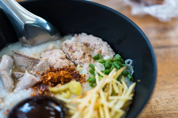 Kıymalı pirinç lapası, domuz sakatatı, kızarmış sarımsak kıymalı domuz eti ve siyah kasede korunmuş yumurta. Asya kahvaltısı.