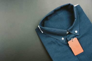 Koyu mavi, uzun kollu, kırmızı kağıt etiketli erkek gömleği.