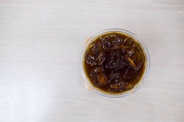 Buzlu sade kahveyle dolu, buz küpleriyle parlayan bir bardağın üst görüntüsü.