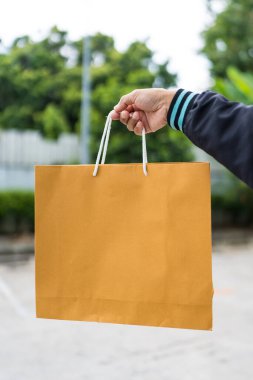 Açık havada kahverengi kağıt poşetler taşıyan biri.