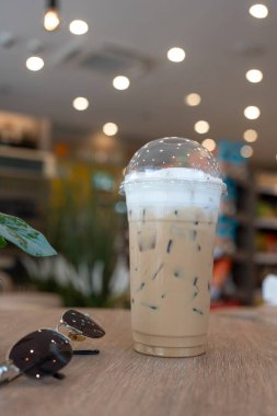 Buzlu kahve ve tahta masanın üzerinde güneş gözlüğü.