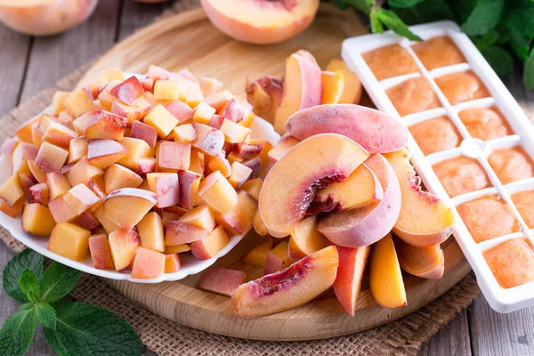 Frozen peaches on a wooden board (slices, slices, puree)