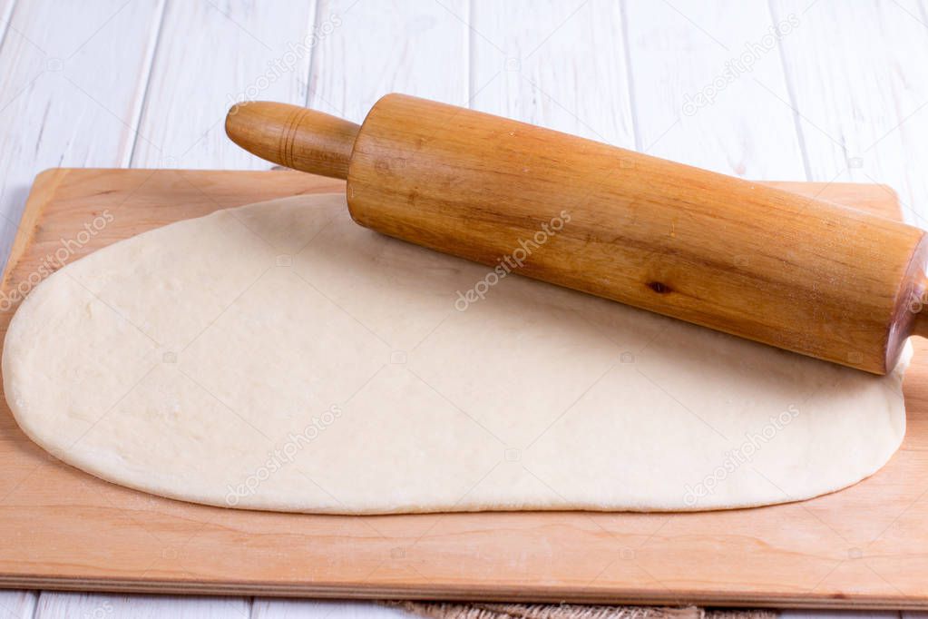 Fresh raw dough and rolling pin on wooden background
