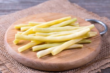 Ahşap bir masa üzerinde bir kesme tahtası üzerinde taze çiğ yeşil fasulye