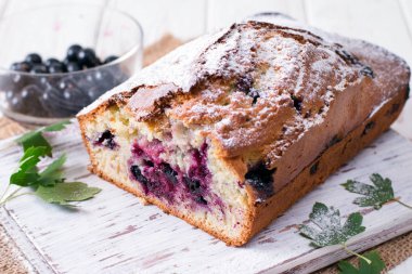 Ahşap kesme tahtası üzerinde siyah frenk üzümü ile pasta.