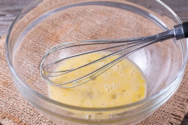 Schneebesen Und Braune Eier Einer Glasschüssel Auf Dem Tisch — Stockfoto