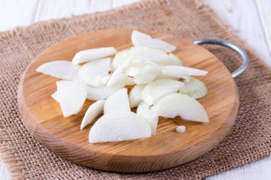 Ahşap bir masa üzerinde bir kesme tahtası üzerinde soğan dilimlenmiş