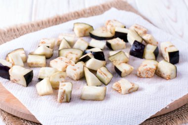 Eggplant cubes on a paper towel on the table clipart