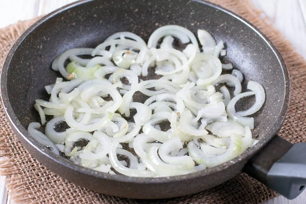 stock image Chopped onion in a frying pan on a wooden table