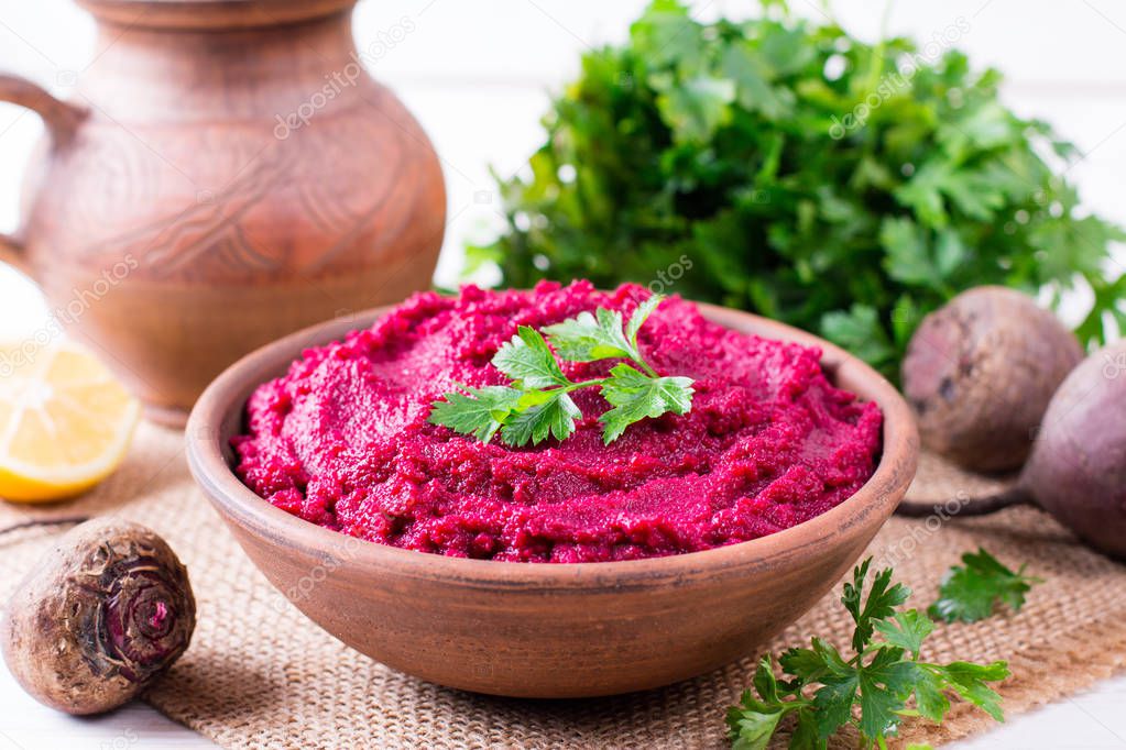 Beet hummus, creamy and delicious in a ceramic bowl on a wooden background