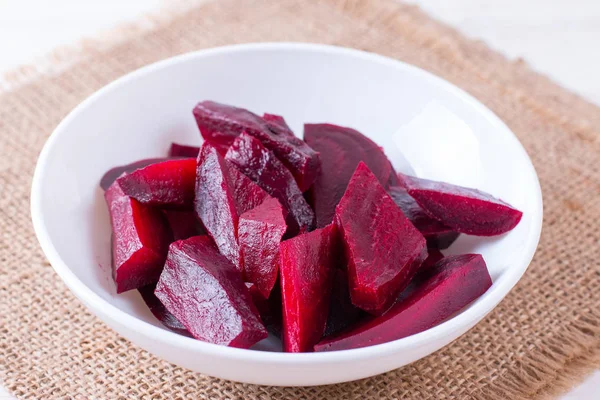 Sliced organic beet root on a white plate on a wooden table