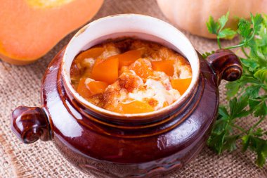 Ahşap bir masa üzerinde bir seramik tencere içinde pişmiş kabak