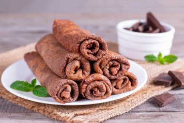 İnce krep veya blinis rustik ahşap arka plan üzerinde plaka üzerinde çikolata kremalı