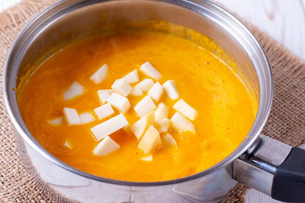Pumpkin soup in a pan with slices of cheese on the table — Stock Image Pumpkin soup in a pan with slices of cheese on the table Stock Picture
