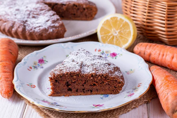 Chocolate cake with carrots in a bowl on a wooden table — Stock Photo, Image