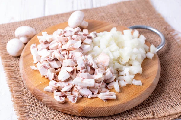 Sliced onions and champignons on a cutting board on a table — Stock Photo, Image