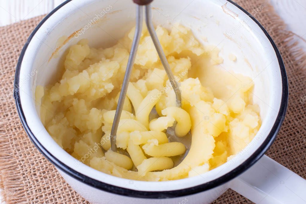 Creamy mashed potato in saucepan on a wooden table