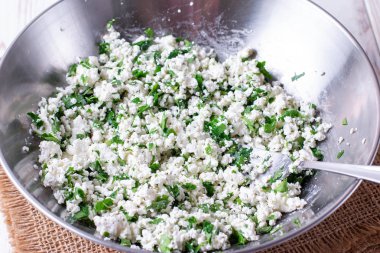 Metal bir kase içinde otlar ve baharatlar ile taze süzme peynir