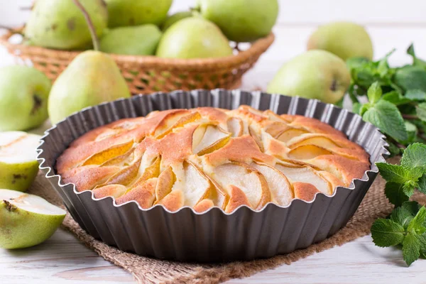 Homemade pear pie on a white table with pears