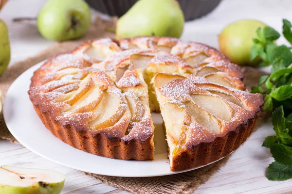 Homemade pear pie on a white table with pears
