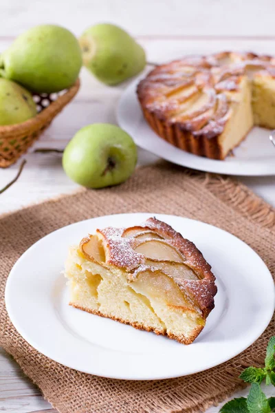 Pièce d'un gâteau aux poires sur une assiette blanche sur une table blanche aux poires — Photo