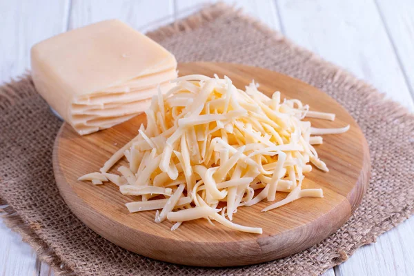 Reszelt sajt egy fa vágódeszka — Stock Fotó