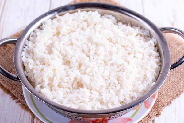 Gekookte rijst in een vergiet op een houten tafel — Stockfoto