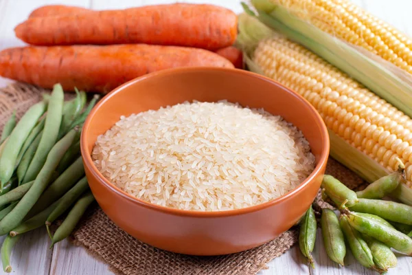 Rice in a ceramic bowl on the background of vegetables — Stock Photo, Image