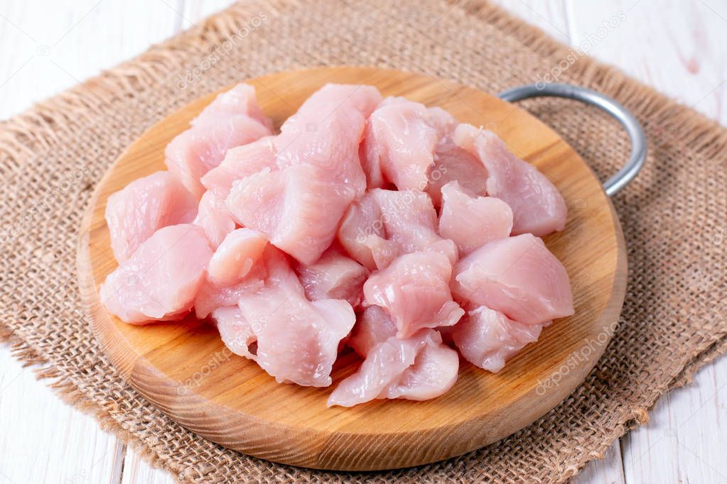 Close up of raw chicken fillet chunks on wood surface