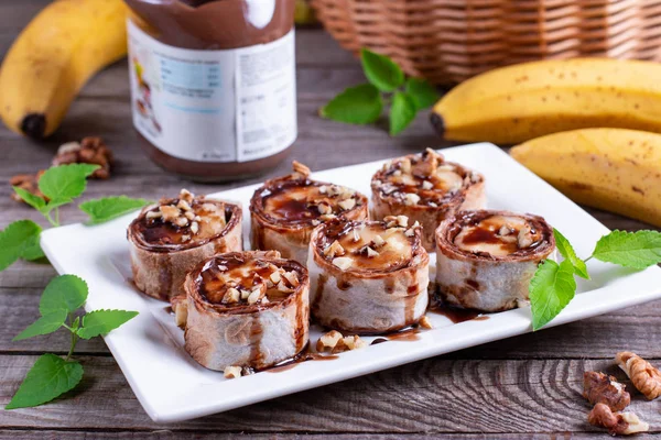 Delicious roll with banana slices on wooden background