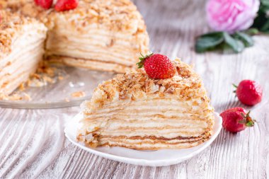 Napolyon 'u beyaz tabağa koymak çocuk oyuncağı. Rus mutfağı, kremalı katmanlı pasta, manzarayı kapat.